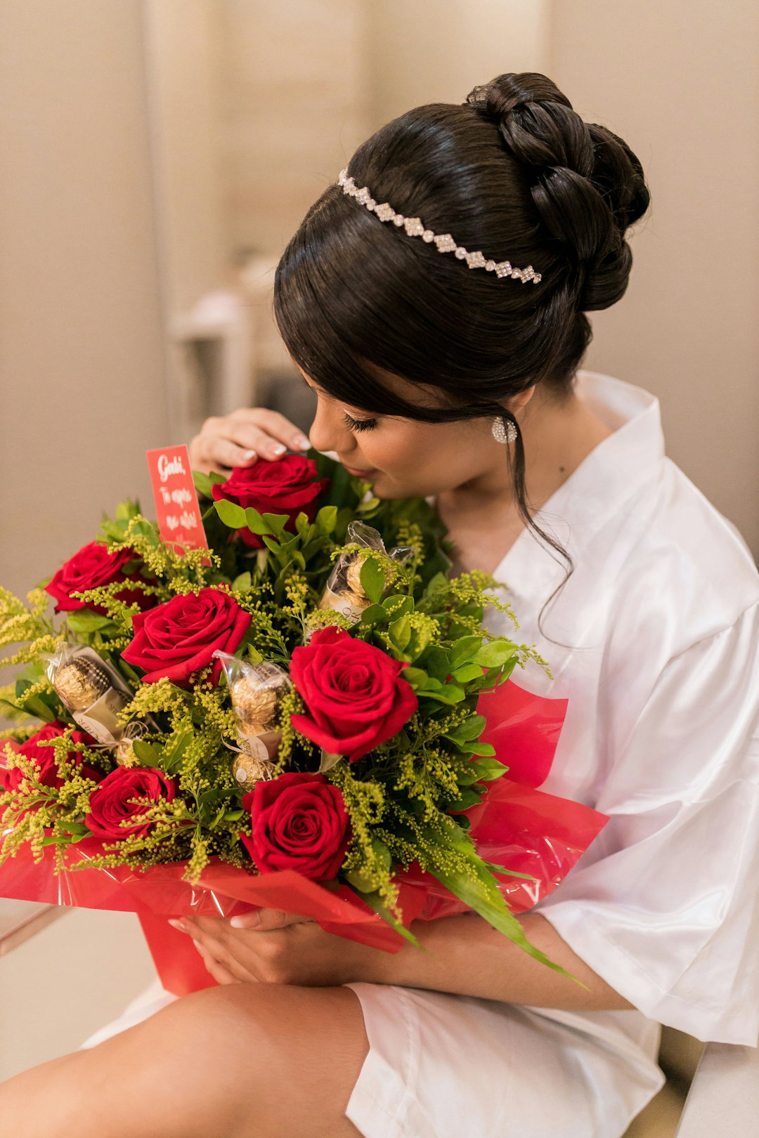 a woman in a white robe holding a bouquet of red roses